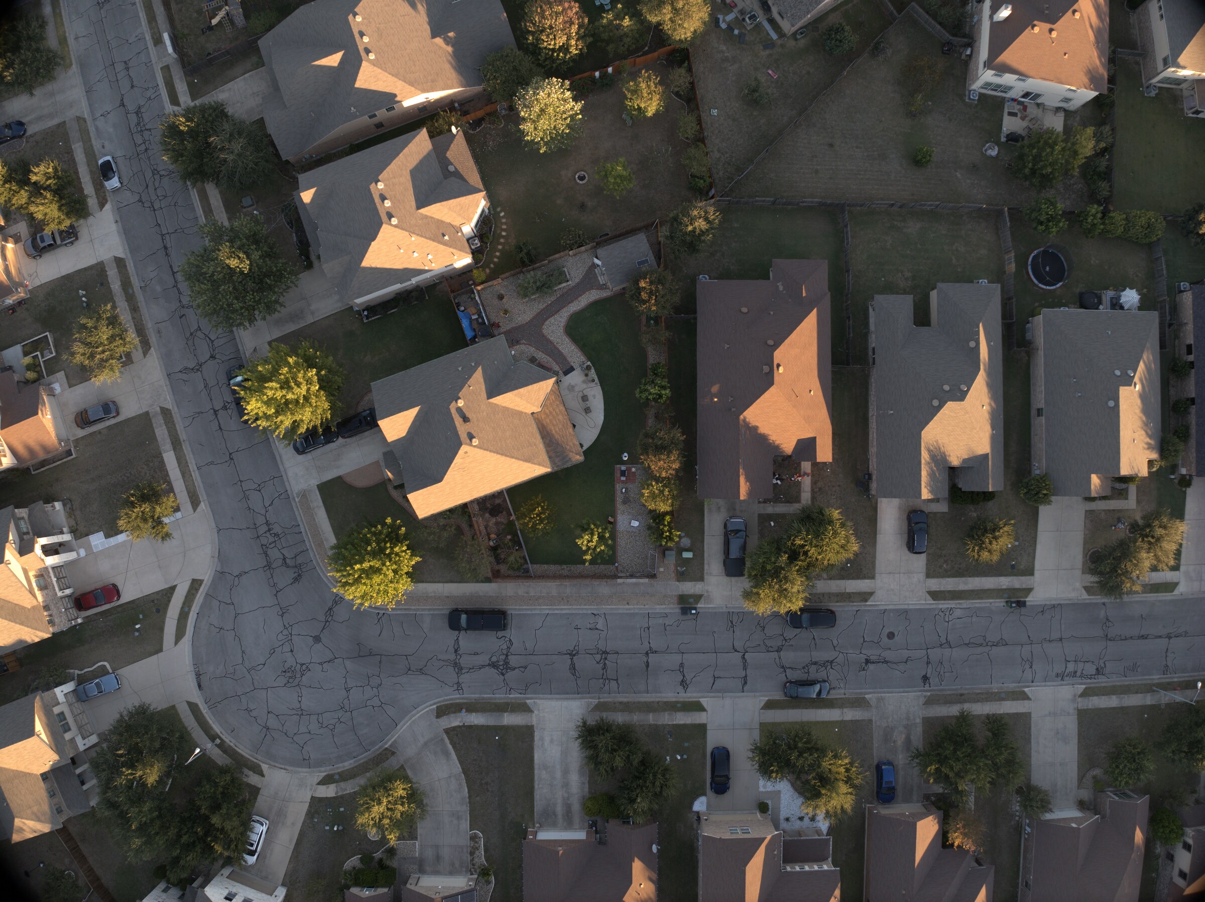 Top-down aerial photograph of Round Rock homes, streets, and long late-day shadows